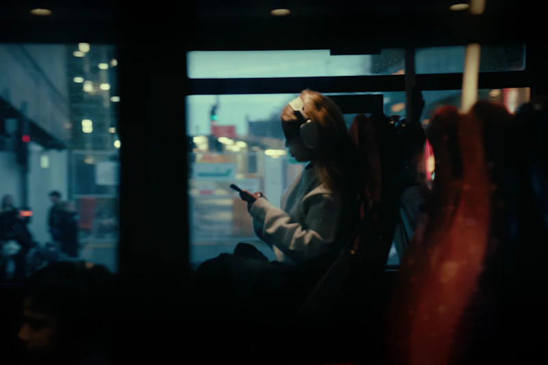A woman on a bus at night, looking at her phone
