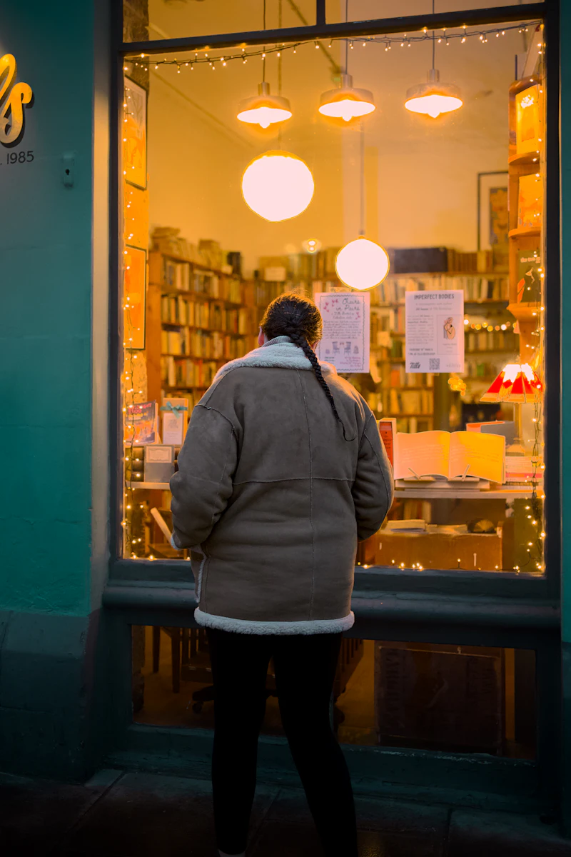 Someone looking into a lit bookshop window at night