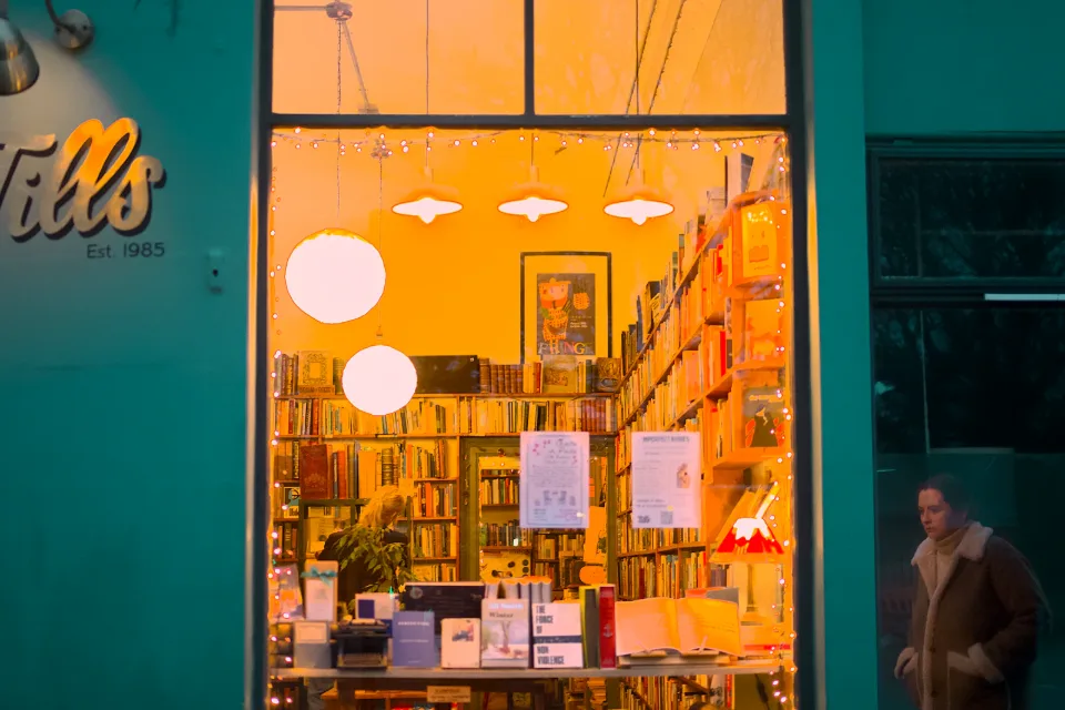 A bookshop window lit at night, a passer-by in the street