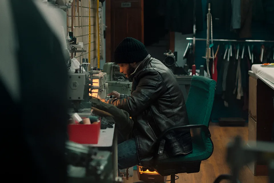 A tailor working at a sewing machine in a small workshop